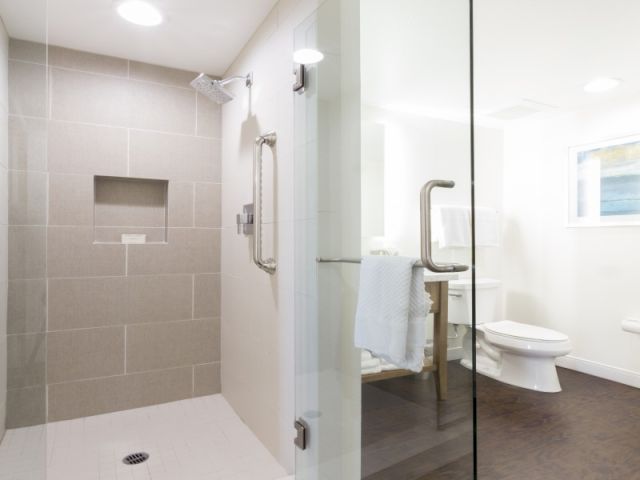 A small, neatly furnished hallway leading to a bright, airy study or bedroom; light walls, a desk, chair, and a door at the end, cozy and tidy.