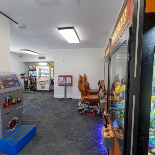 An indoor arcade with touchscreen game machines, claw machines, prize prizes, and a glass cabinet with plush toys.