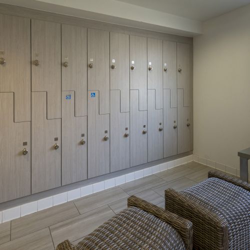A row of apartment mailboxes/lockers with numbers and accessibility icons lines the wall, with a bench and wicker baskets nearby.